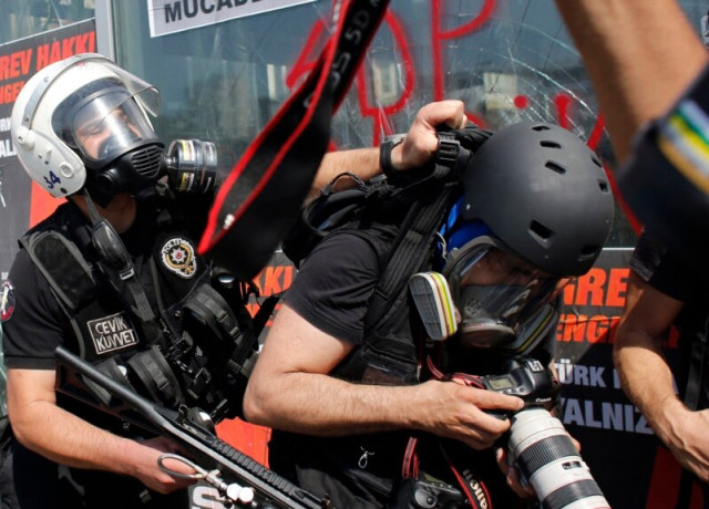 A Turkish riot policeman pushes a photographer during a protest at Taksim Square in Istanbul, June 11, 2013.